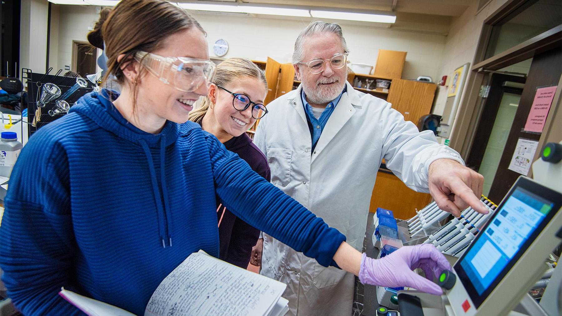 Dr. Peliska working in a lab class with students.